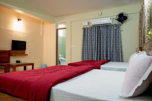 um quarto com uma cama grande e um cobertor vermelho em HILL PALACE RESIDENCY COORG em Virajpet