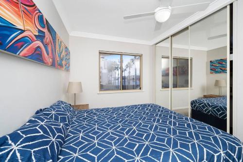 a bedroom with a blue and white bed and windows at Sandcastles At The Beach Outstanding Location! in Perth