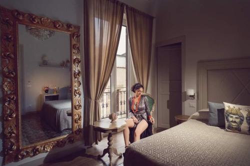 Kèramos Luxury Rooms في شاكا: امرأة تجلس على كرسي أمام مرآة