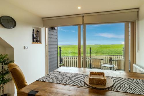 a dining room with a table and a view of a deck at Picturesque cottage with views 