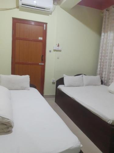 2 camas en una habitación con puerta en Om siddhababa Restaurant and Lodge, en Bharatpur