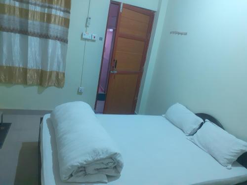una habitación de hospital con una cama blanca y una puerta en Om siddhababa Restaurant and Lodge, en Bharatpur