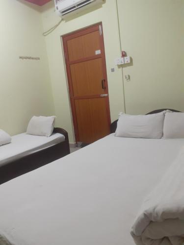 Dos camas en una habitación con una puerta. en Om siddhababa Restaurant and Lodge, en Bharatpur