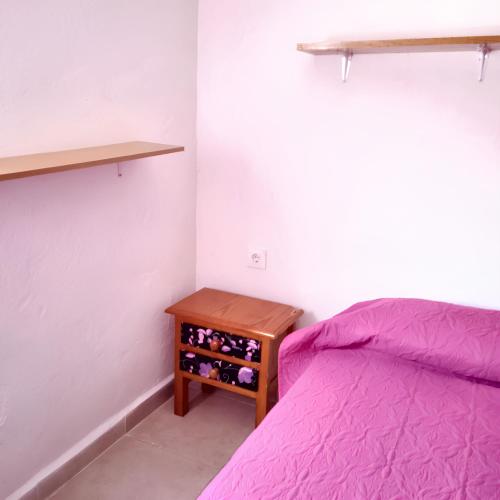 Schlafzimmer mit einem lila Bett und einem Holztisch in der Unterkunft 2 bedrooms house at Ciudad Real in Ciudad Real
