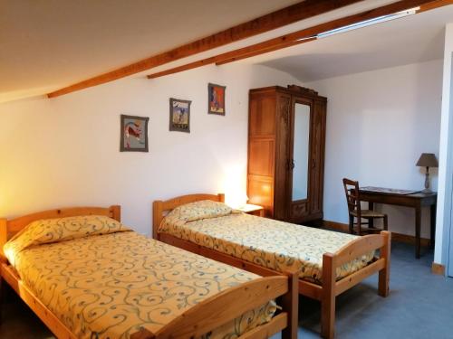 a bedroom with two beds and a desk at Logis de Flamenac in Pranzac