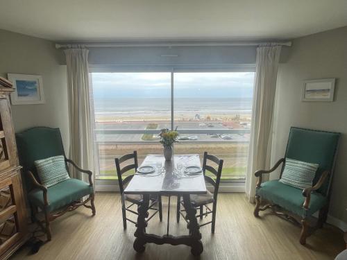 une salle à manger avec une table et des chaises et une grande fenêtre dans l'établissement Studio Front Mer, à Le Touquet-Paris-Plage