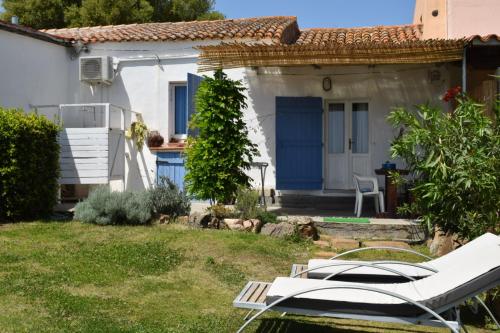 een klein wit huis met blauwe deuren en stoelen bij Sa Domitta di Suiles in Olbia