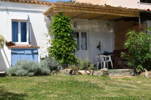 Casa blanca con porche con mesa y sillas en Sa Domitta di Suiles en Olbia