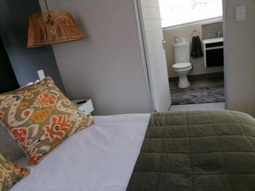 a bedroom with a bed and a bathroom with a toilet at Shingalana Cottages in White River