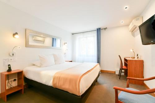 una camera da letto con un letto, una scrivania e una TV di Logis Hotel & Restaurant Bergeret Sport a Hendaye