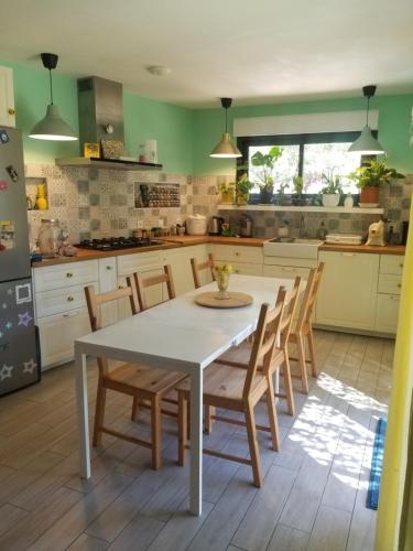 - une cuisine avec une table et des chaises blanches dans l'établissement Grande villa 2 min plage - plein centre, à Vias