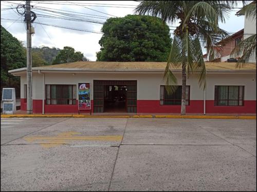 un edificio rosso e bianco con una palma di fronte di COE RURRENABAQUE a Rurrenabaque