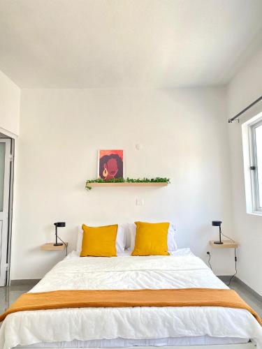 a bedroom with a large bed with two yellow pillows at Vila de Santiago Apartment in Pedra Badejo