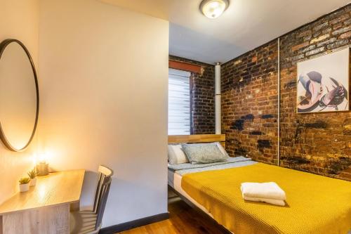 a bedroom with a yellow bed and a brick wall at Heavenly Suites in Perfect Location of Hell Kitchen in New York