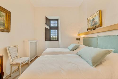 a bedroom with two beds and a chair and a window at Château de Saint Vidal in Le Puy en Velay