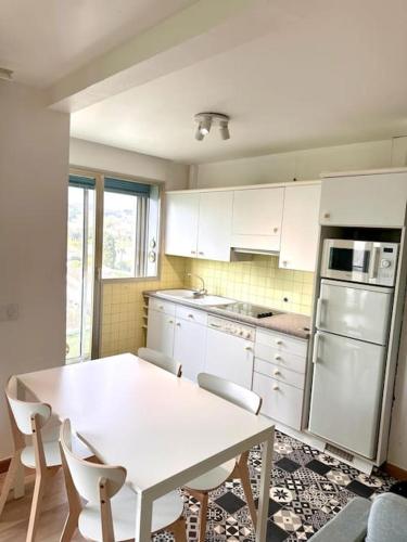une cuisine avec des armoires blanches et une table et des chaises dans l'établissement 108 Cagnes - Joli T2 avec balcon proche mer, à Cagnes-sur-Mer