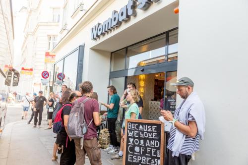 un gruppo di persone che si trovano fuori da un negozio di Wombat's City Hostel Vienna Naschmarkt a Vienna