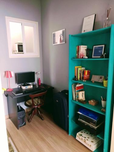 a green book shelf with a desk and a computer at Apartamento Parque Jardim Europa in Rio de Janeiro