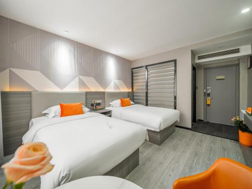 a hotel room with two beds with orange pillows at Orient Rose International Hotel in Shanghai