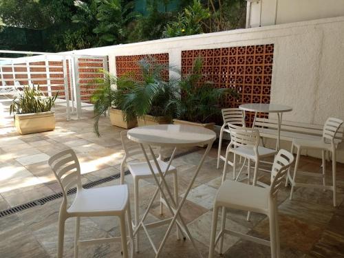 un patio con mesas, sillas blancas y plantas en Apartamento Parque Jardim Europa, en Río de Janeiro