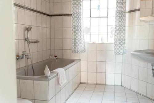 Baño blanco con bañera y lavamanos en Ferienhaus Steinhoff, en Marsberg