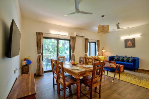 a dining room and living room with a table and chairs at Lavish 2BHK Apartment with Swimming Pool in Candolim in Candolim