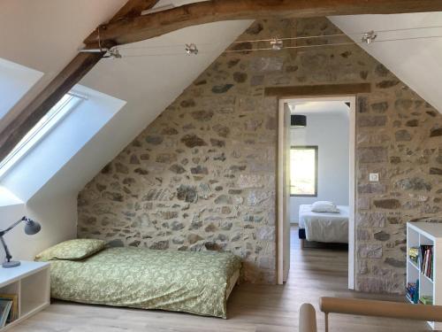 un dormitorio en el ático con una pared de piedra y una cama en Erquy Les Hirondelles, en Erquy