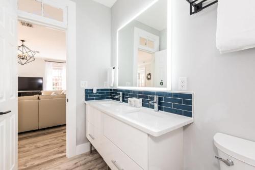 a white bathroom with a sink and a mirror at 20 Hypolita - Luxury Downtown Apartment in St. Augustine