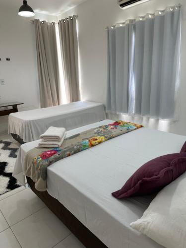 2 Betten in einem Schlafzimmer mit weißen Wänden und Vorhängen in der Unterkunft SUITE ELEGACY in Serra de São Bento