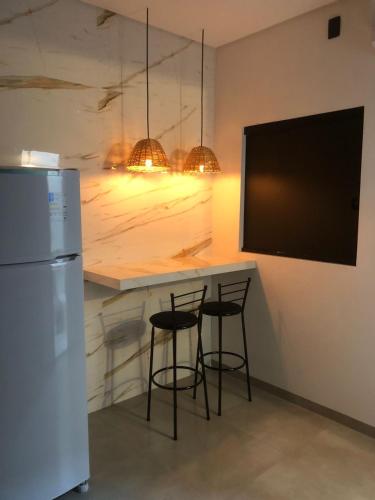 une cuisine avec deux tabourets de bar et une télévision dans l'établissement Lofts Paraíso, à Luís Eduardo Magalhães