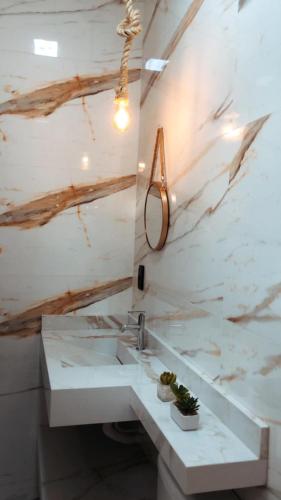 La salle de bains est pourvue d'un lavabo et d'un mur en marbre. dans l'établissement Lofts Paraíso, à Luís Eduardo Magalhães