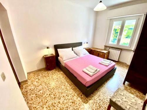 1 dormitorio con 1 cama rosa y 2 toallas en La Residenza dell'Arrotino, en Capitan Loreto