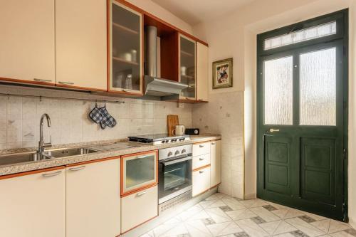 a kitchen with white cabinets and a green door at Casa Luana San Concordio - Affitti Brevi Italia in Lucca