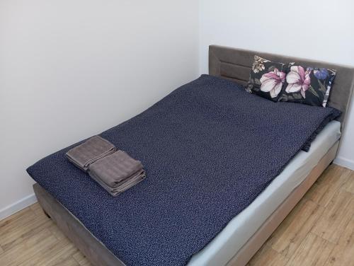 a bed with a blue blanket and a purse on it at Apartament Aleja Lipowa in Górki Wielkie