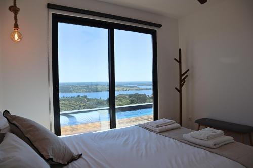 a bedroom with a bed and a large window at Caju Villas Montargil - Villa Vale Vilão in Montargil