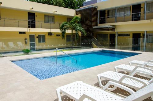 a swimming pool with chairs and a building at Hotel Arizona Suites Cúcuta in Cúcuta