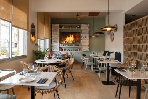ein Restaurant mit Tischen und Stühlen und einem Kamin in der Unterkunft Hôtel BO & MIA in La Baule