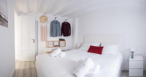 ein weißes Schlafzimmer mit einem weißen Bett und roten Kissen in der Unterkunft TuApartamento El Mirador de la Estafeta in Pamplona