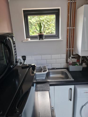 una pequeña cocina con fregadero y ventana en 1 Bed Annex 2 mins from Harlow Mill train station, en Harlow