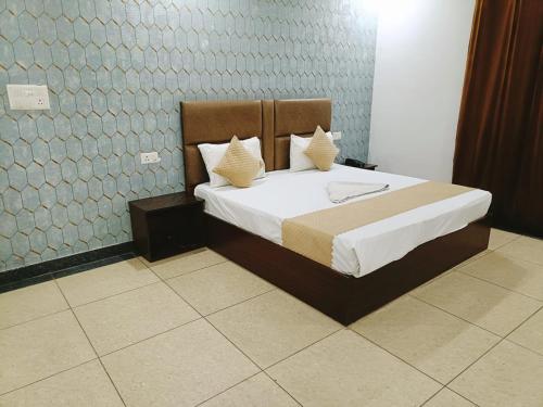 um quarto com uma cama com lençóis brancos e almofadas em Hotel Ambience Palace Near IGI Airport Delhi em Nova Deli