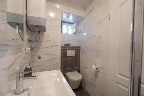 a white bathroom with a toilet and a sink at Studio Banovac in Dubrovnik