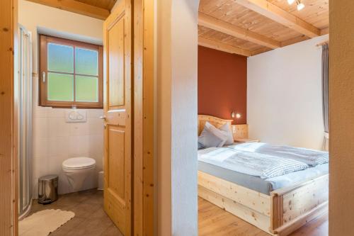 1 Schlafzimmer mit einem Holzbett und einem Badezimmer in der Unterkunft Ronsolhof Schlern in Seis am Schlern