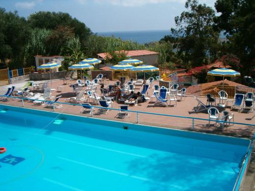 uma piscina com um monte de cadeiras e guarda-sóis em Villaggio Residence Villamarina em Marina di Camerota