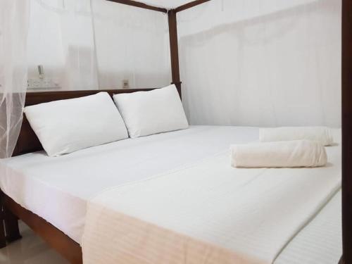 duże białe łóżko z 2 poduszkami w obiekcie Elegarden hotel and Restaurant Udawalawe w mieście Udawalawe