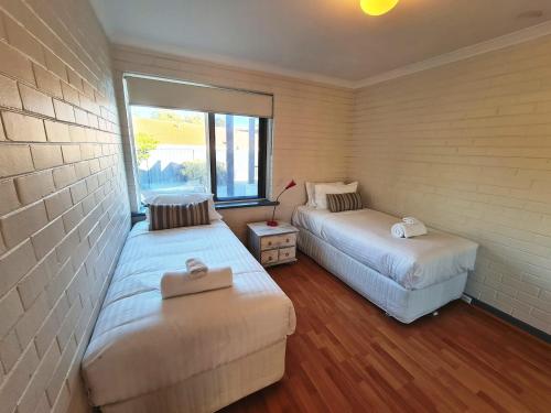 um pequeno quarto com 2 camas e uma janela em Ocean's "4" Holiday Or Business Stay Accommodation em Perth