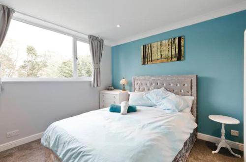 a bedroom with a white bed with a blue wall at StayInWoking at 30 Woodlands in Horsell