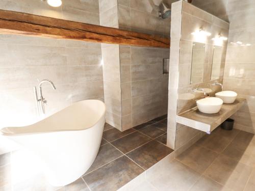 a bathroom with a white tub and two sinks at The Old Barn in Market Rasen