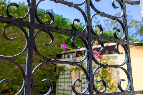 a black iron gate with pink flowers in the background at Logis Hotel l'Esterella in Agay - Saint Raphael