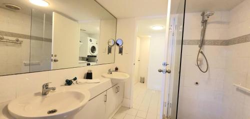 a white bathroom with a sink and a shower at Sandcastles Beachfront Luxury Retreat Apartment in Perth