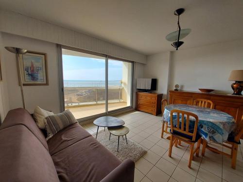 un salon avec un canapé, une table et une fenêtre dans l'établissement La baie et mer de Sion, à Saint-Hilaire-de-Riez